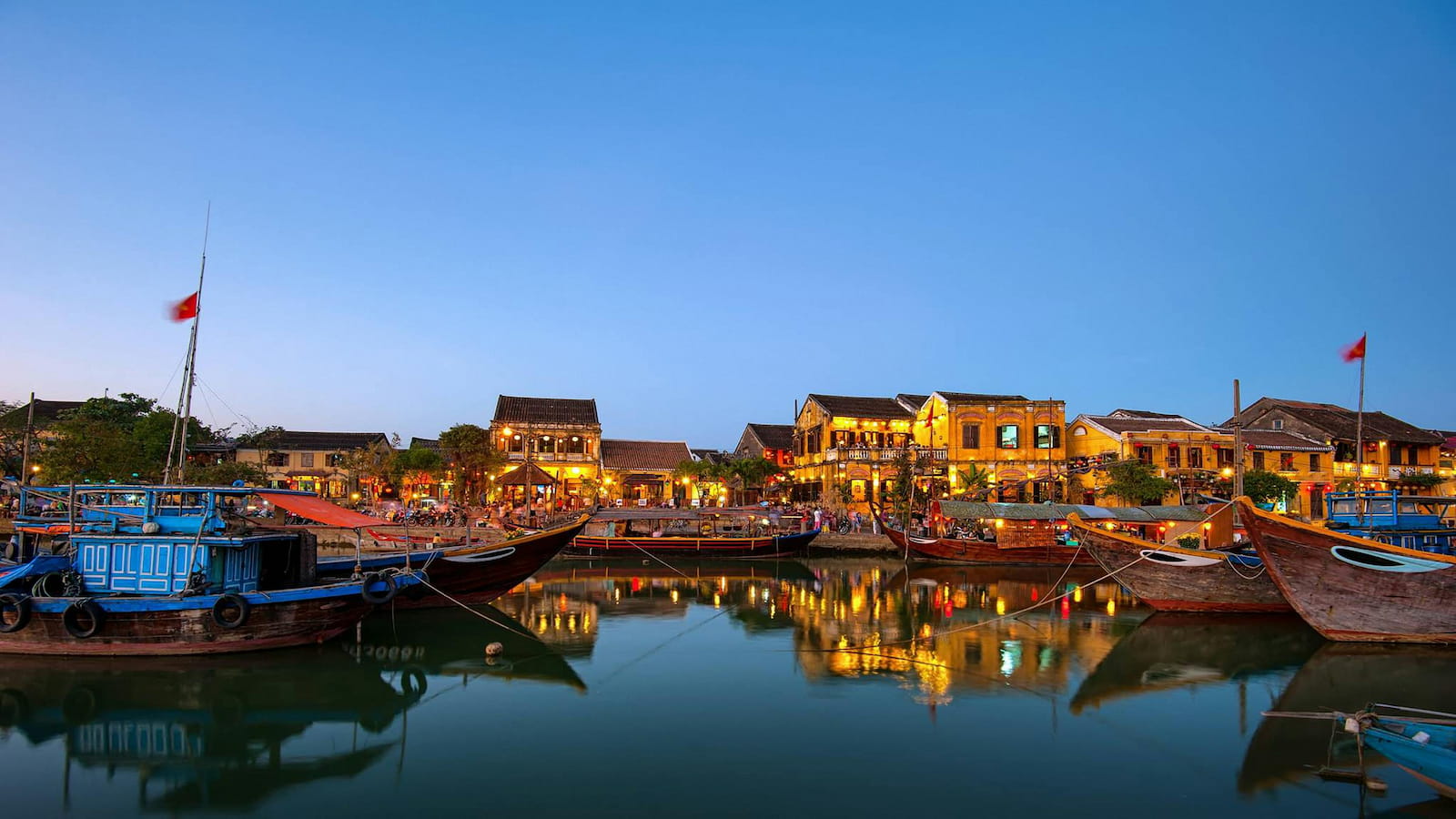 Night falls gently as lanterns bloom in Hoi An